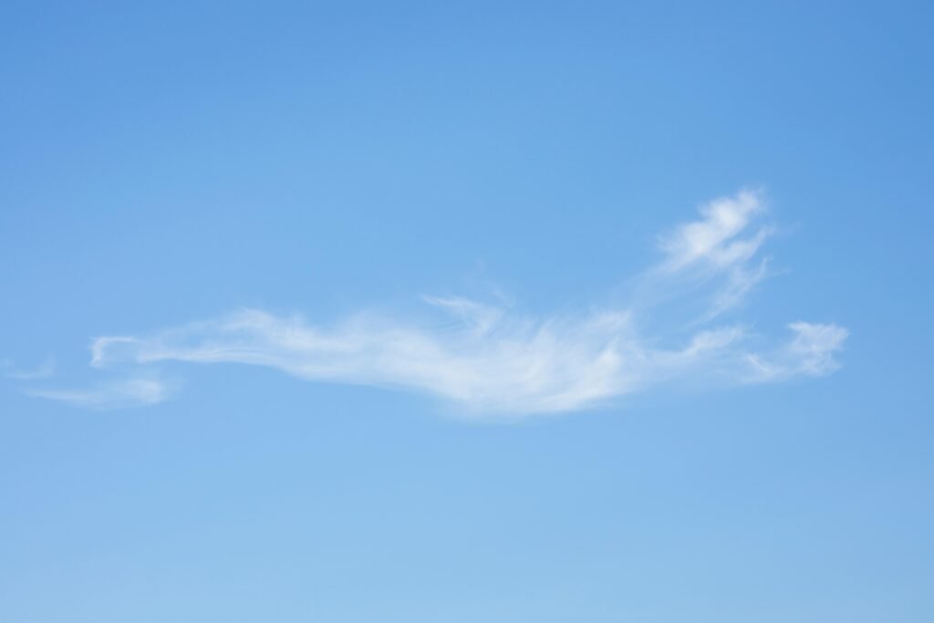 An artistic capture of a single wispy cloud in a vast blue sky, conveying tranquility.