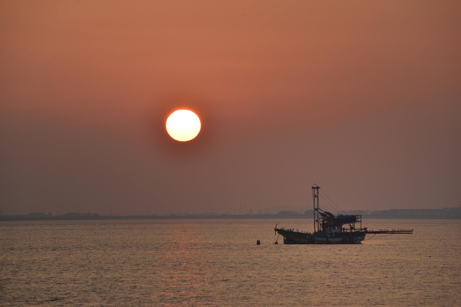 Serene view of a fishing boat at sunset over Incheon's waters, reflecting calmness.